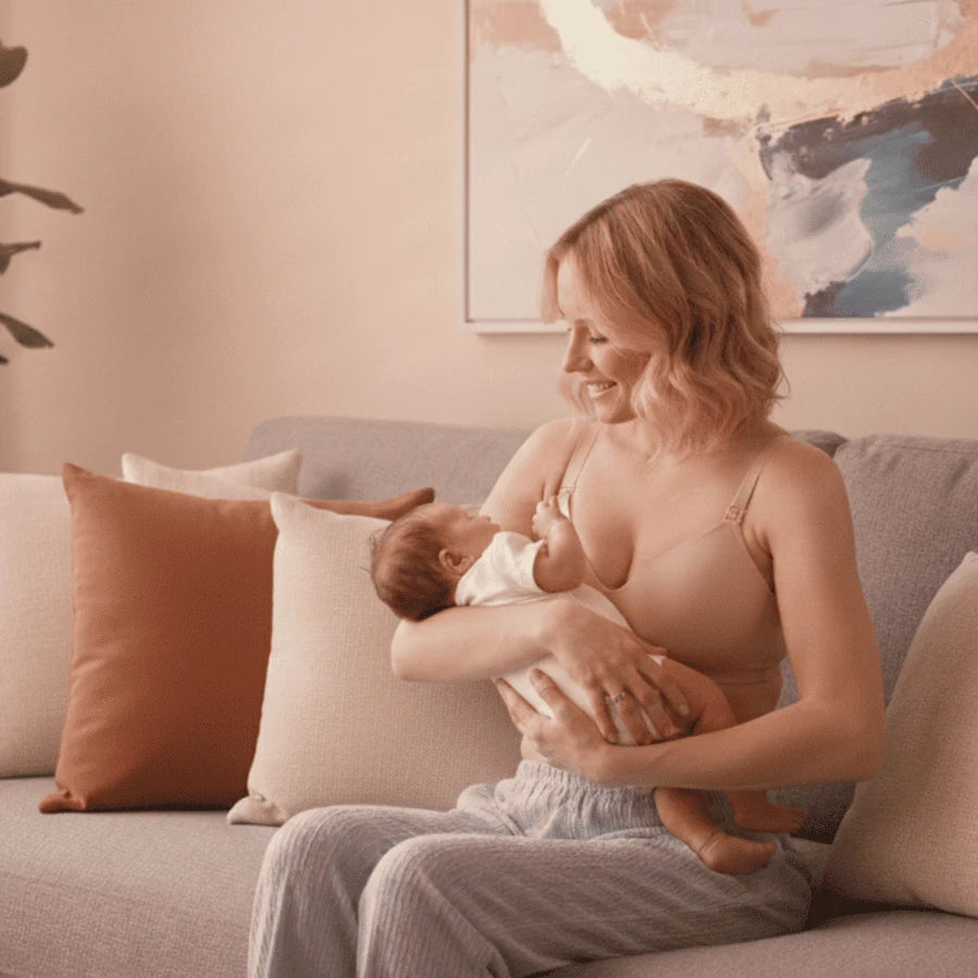 Jeune maman blonde tenant son bébé dans ses bras avec tendresse dans un salon au design moderne