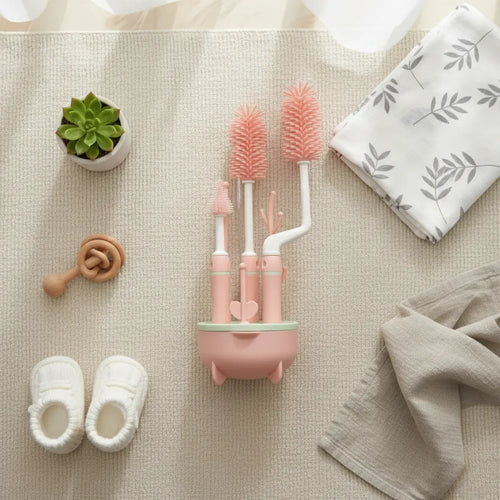 Kit de brosses de nettoyage pour biberon bébé avec support silicone et accessoires disposés dans un univers bébé