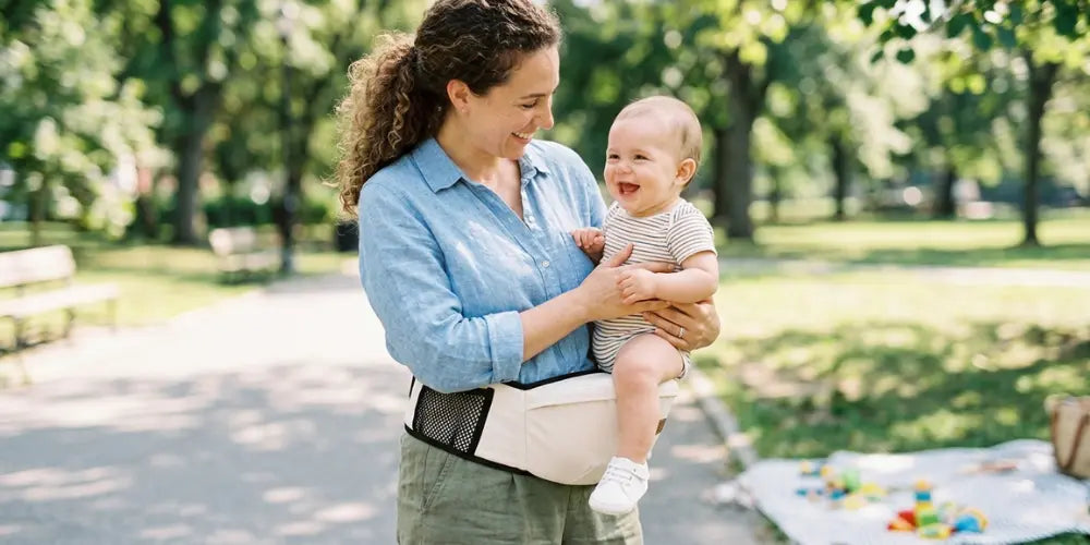 Maman portant bébé avec ceinture de portage hanche ergonomique en extérieur pour confort et liberté de mouvement