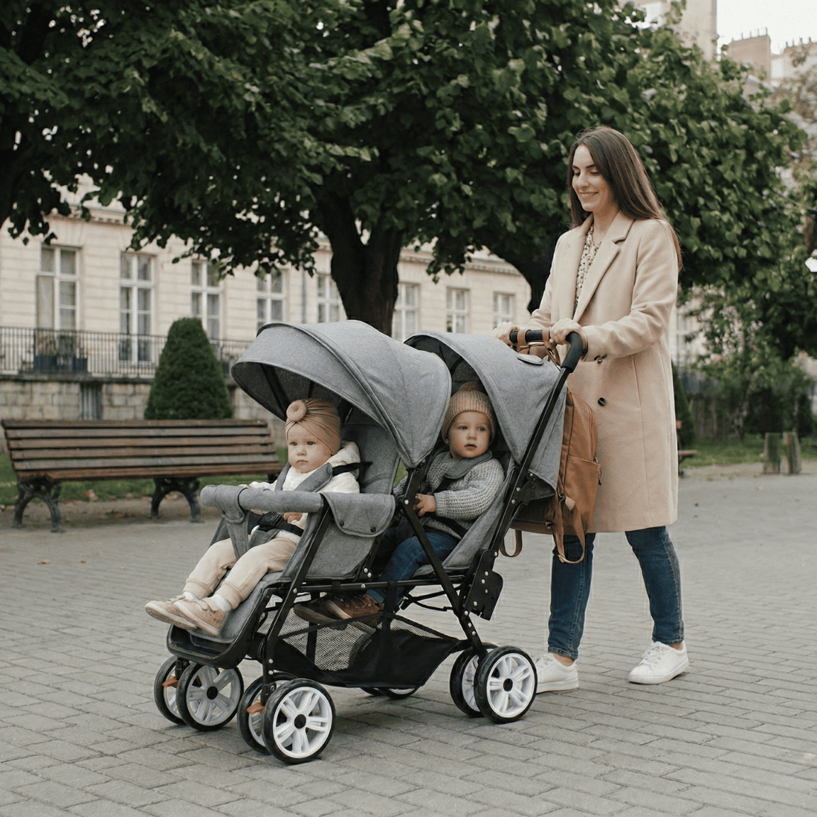 Femme élégante utilisant une poussette double grise pour jumeaux en ville, mettant en avant le design moderne et la facilité d'utilisation au quotidien.